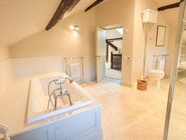 A bathroom with a bathtub toilet and door leading to another room at Green Yew in Winster near Bowness-On-Windermere