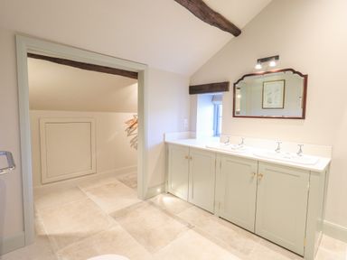 A bathroom with double sink vanity mirror tiled floor and a small adjacent closet space at Green Yew in Winster near Bowness-On-Windermere