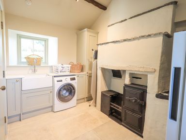 A laundry room with a washing machine sink baskets and an old stove at Green Yew in Winster near Bowness-On-Windermere
