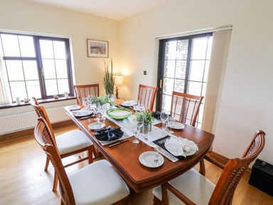 A dining room with a wooden table set for six people with plates glasses and napkins at Doonalton House in Dromore West County Sligo