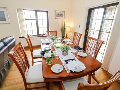 A dining room with a wooden table set for a meal with six chairs at Doonalton House in Dromore West County Sligo