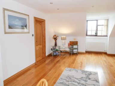 A corner of a room with wooden floor a door framed picture a glass table with lamp and decor and a window with a plant at Doonalton House in Dromore West County Sligo