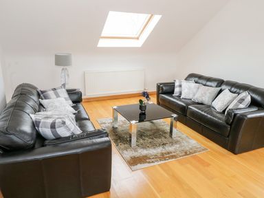 A living room with two black leather sofas a glass coffee table and a skylight window at Doonalton House in Dromore West County Sligo