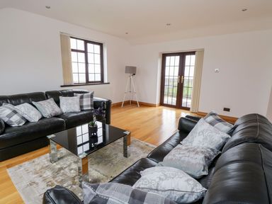 A living room with two black leather sofas and a glass coffee table at Doonalton House in Dromore West County Sligo