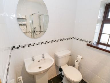 A bathroom with a sink toilet mirror and window at Doonalton House in Dromore West County Sligo