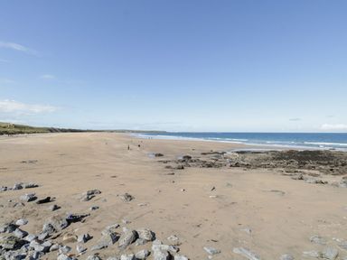 A sandy beach with rocks and few people near the ocean at Doonalton House in Dromore West County Sligo