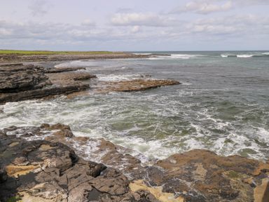 A rocky shoreline with waves by the ocean at Doonalton House in Dromore West, County Sligo