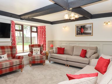 A living room with beige sofas red cushions and plaid armchairs near a window at Nempnett Farmhouse in Nempnett Thrubwell near Blagdon