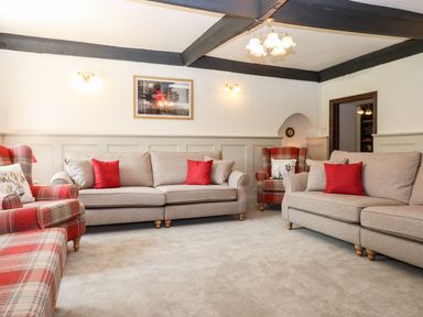 A living room with beige sofas and red plaid armchairs at Nempnett Farmhouse in Nempnett Thrubwell near Blagdon