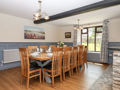 A dining room with a long wooden table and chairs set with plates and glasses at Nempnett Farmhouse in Nempnett Thrubwell near Blagdon