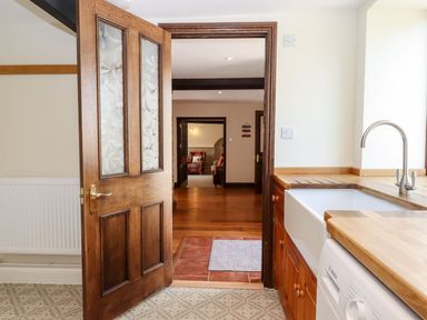 A kitchen with a wooden door open to a hallway and living room at Nempnett Farmhouse in Nempnett Thrubwell near Blagdon