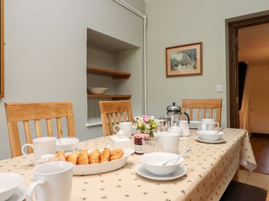 A dining room with a table set for breakfast with croissants cups a coffee press and a flower vase at Nempnett Farmhouse in Nempnett Thrubwell near Blagdon