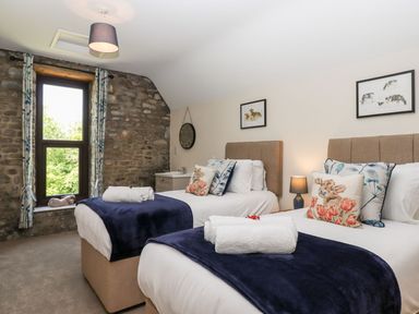 A bedroom with two single beds with blue blankets and animal print cushions at Nempnett Farmhouse in Nempnett Thrubwell near Blagdon