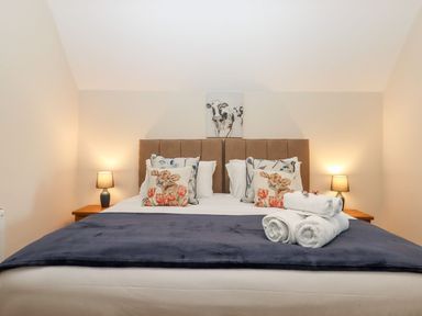 A bedroom with a double bed with animal print cushions and rolled towels on a blue bedspread at Nempnett Farmhouse in Nempnett Thrubwell near Blagdon