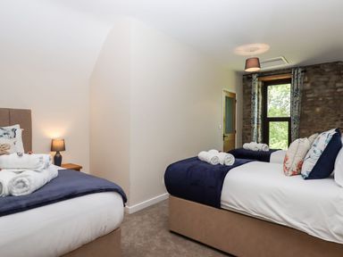 A bedroom with two beds with rolled towels on them and a window with stone wall at Nempnett Farmhouse Nempnett Thrubwell near Blagdon