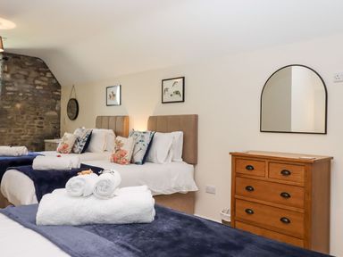 A bedroom with two beds with pillows and towels a wooden dresser with a mirror and a stone wall section at Nempnett Farmhouse in Nempnett Thrubwell near Blagdon