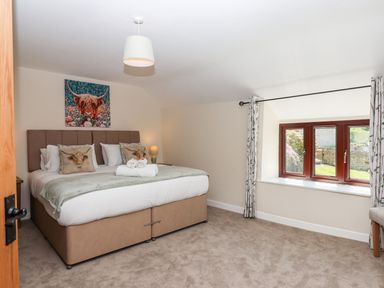 A bedroom with a double bed towels on bed and a window with curtains at Nempnett Farmhouse in Nempnett Thrubwell near Blagdon