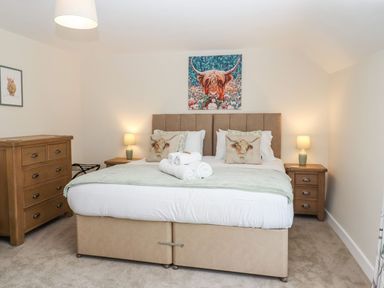 A bedroom with a bed two bedside tables with lamps a dresser and animal artwork at Nempnett Farmhouse Nempnett Thrubwell near Blagdon