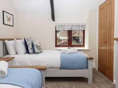 A bedroom with two beds with blue blankets and rolled towels by a window and a wooden door at Nempnett Farmhouse Nempnett Thrubwell near Blagdon