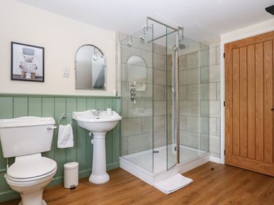 A bathroom with a toilet sink glass shower and wooden door at Nempnett Farmhouse in Nempnett Thrubwell near Blagdon