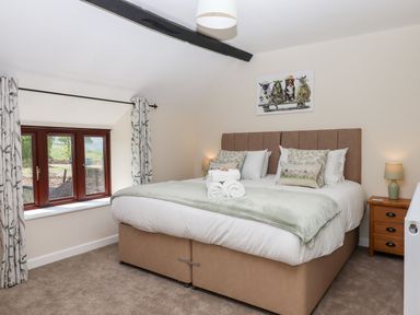 A bedroom with a double bed bedside tables lamps windows and curtains at Nempnett Farmhouse in Nempnett Thrubwell near Blagdon
