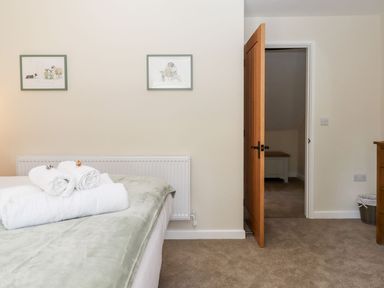 A bedroom with rolled towels on the bed two framed pictures on the wall an open door and carpeted floor at Nempnett Farmhouse in Nempnett Thrubwell near Blagdon