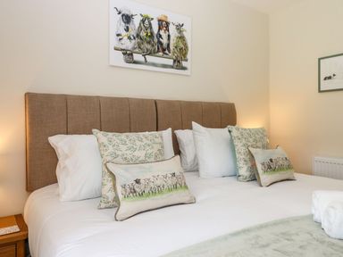 A bedroom with a bed featuring decorative pillows and a padded headboard at Nempnett Farmhouse in Nempnett Thrubwell near Blagdon