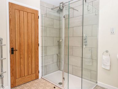 A bathroom with a glass shower enclosure a wooden door and a towel hanging on a ring at Nempnett Farmhouse in Nempnett Thrubwell near Blagdon