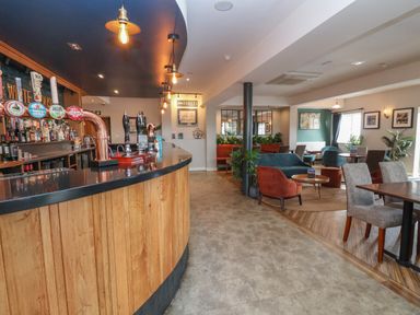 An interior view of a bar area with wooden counters and seating at Lodge 3 in St Asaph