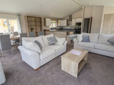 A living room with two sofas a coffee table and a dining table in an open plan layout at Lodge 3 in St Asaph