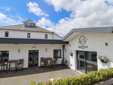 The exterior of a white building with outdoor tables and chairs and a bicycle near the entrance at White Spa in St Asaph