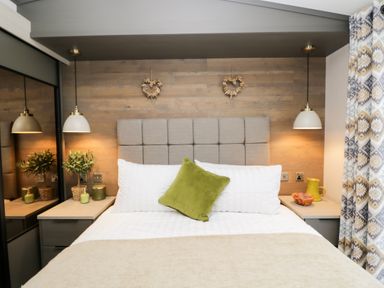 A bedroom with a bed white pillows and a green cushion two bedside tables with lamps and decorative items at Tiggywinkles in Chipping Norton