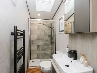 A bathroom with a shower enclosure a toilet a sink with a faucet and a mirrored cabinet at Tiggywinkles in Chipping Norton