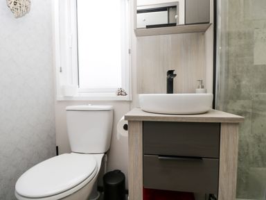 A bathroom with a toilet a sink with a black faucet a cabinet and a window at Tiggywinkles in Chipping Norton