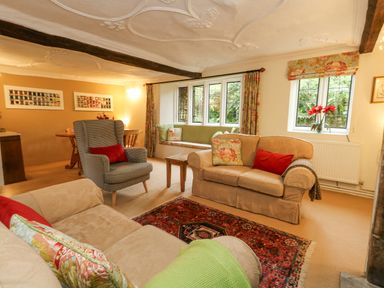 A living room with sofas, armchair, window seat, and dining table at The Elbow in Frampton