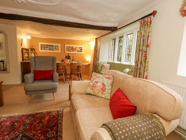 A living room with a sofa and armchair next to a window and a dining table at The Elbow in Frampton