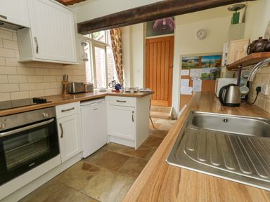 A kitchen with countertop appliances a sink and a wooden door at The Elbow in Frampton