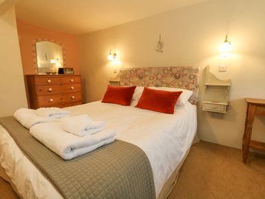 A bedroom with a double bed folded towels wooden chest of drawers and wall lamps at The Elbow in Frampton