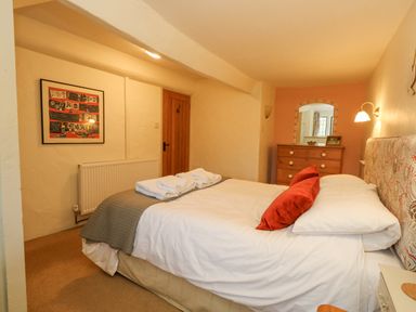 A bedroom with a bed and red pillows a wooden dresser and a framed picture on the wall at The Elbow in Frampton