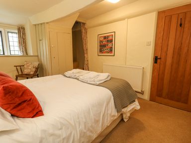 A bedroom with a bed with white and gray bedding a wooden chair a framed picture and a wooden door at The Elbow in Frampton