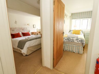 Two bedrooms with beds and bedside tables separated by a hallway at The Elbow in Frampton