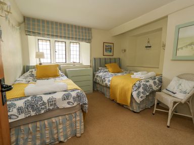 A bedroom with two single beds with yellow pillows and bed runners a chest of drawers and a chair at The Elbow in Frampton