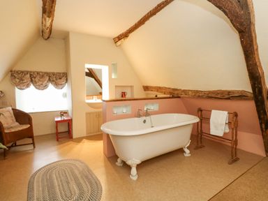 A bathroom with a freestanding bathtub a towel rack a wicker chair and a small table at The Elbow in Frampton