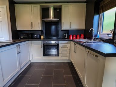 A kitchen with cabinets, sink, microwave and oven at The Red in Llanerch Park near St Asaph