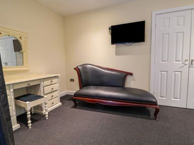 A bedroom with a chaise lounge and a desk at The Red in Llanerch Park near St Asaph