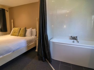 A bedroom with a bed and a bathtub at The Red in Llanerch Park near St Asaph