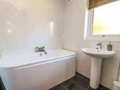 A bathroom with a bathtub, sink, and window at The Red in Llanerch Park near St Asaph