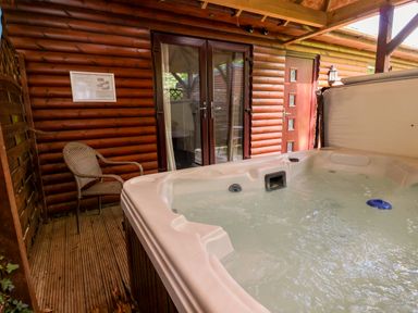 An outdoor area with a hot tub and a chair at The Red in Llanerch Park near St Asaph