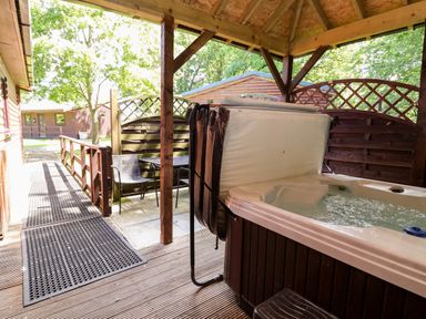 An outdoor area with a hot tub and seating at The Red in Llanerch Park near St Asaph