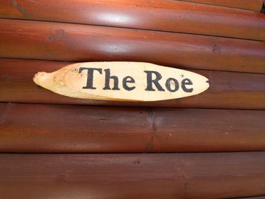 A wooden sign with the text The Roe on a wooden surface at The Roe near Llanerch Park near St Asaph